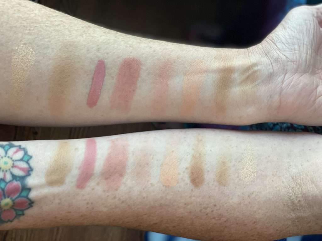 Two pale white arms with seven swatches of blush and bronzer